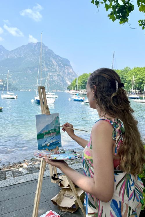 Una ragazza dipinge su una tela in riva al Lago di Como in Lombardia durante il corso di pitture en plein air con i colori ad olio