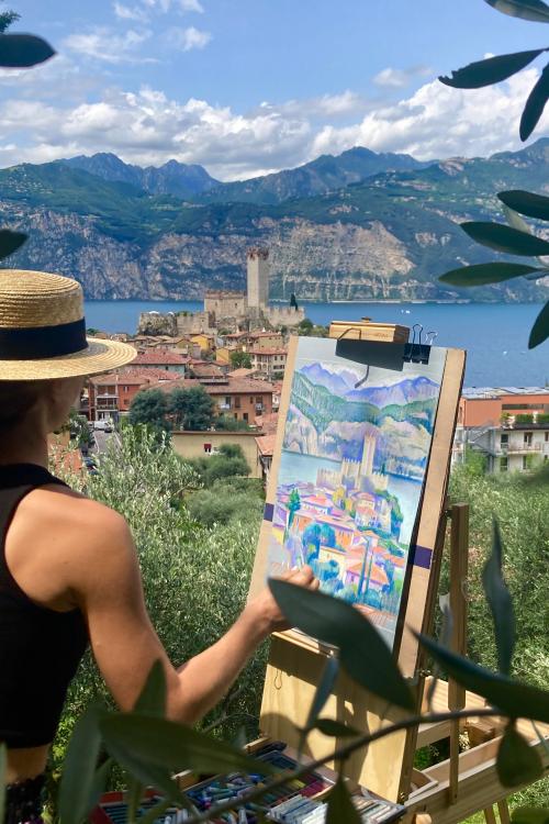 Una ragazza dipinge su una tela con i colori ad olio durante il corso en plein air vicino Varenna sul Lago di Como in Lombardia