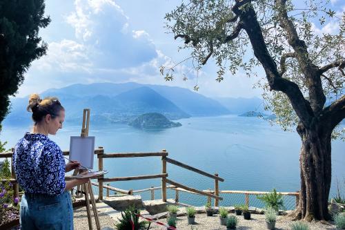 Una ragazza dipinge con i colori ad olio una tela bianca durante il corso all'aria aperta sul Lago di Como in Lombardia nel Castello di Vezio