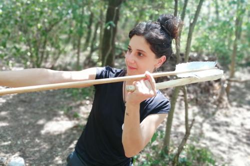 Una ragazza impara a lanciare una freccia durante il corso per imparare a costruire un arco primitivo vicino il Lago di Garda in Lombardia