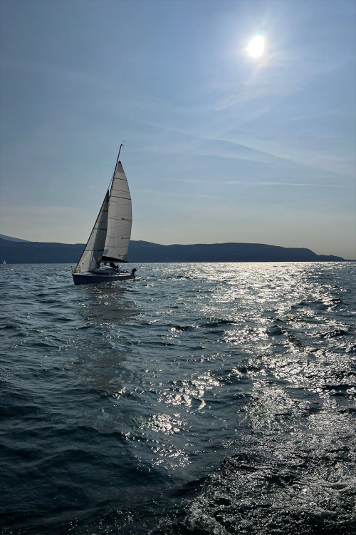 Barca a vela che naviga controluce sul Lago di Garda in Lombardia