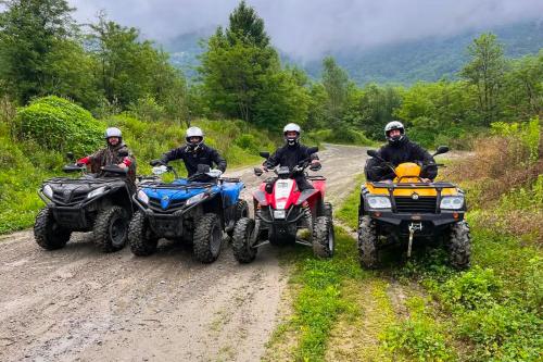 Quattro ragazzi in sella a dei quad sotto la pioggia durante il tour adrenalinico della Valtellina in Lombardia