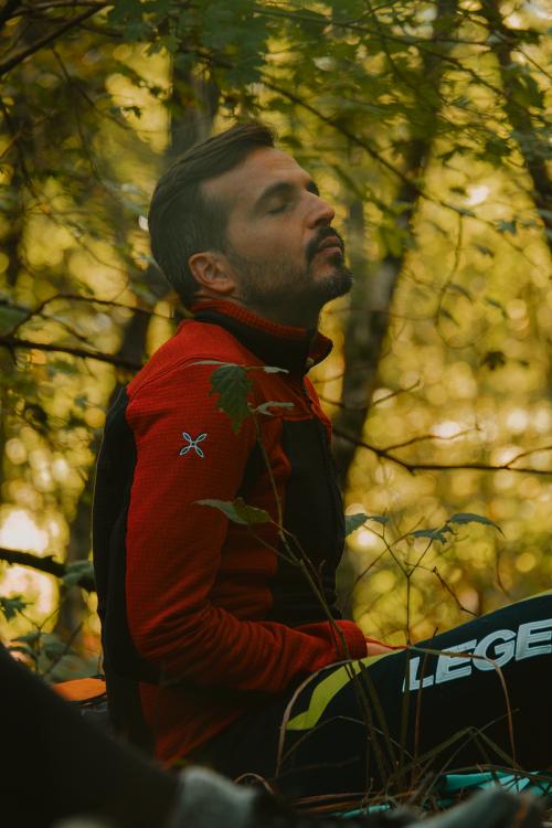 Un ragazzo seduto nella natura mentre medita durante una esperienza di forest bathing in Lombardia nel Parco Regionale di Montevecchia