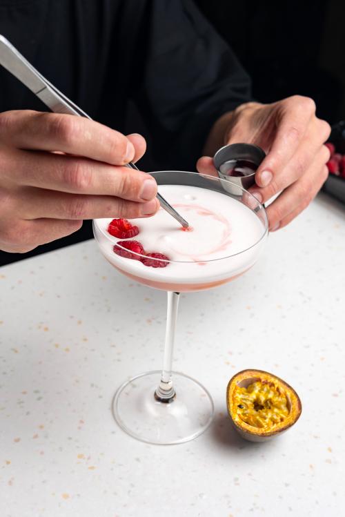 Persona che crea un cocktail con passion fruit e frutti di bosco durante lattività di team building a Milano in Lombardia